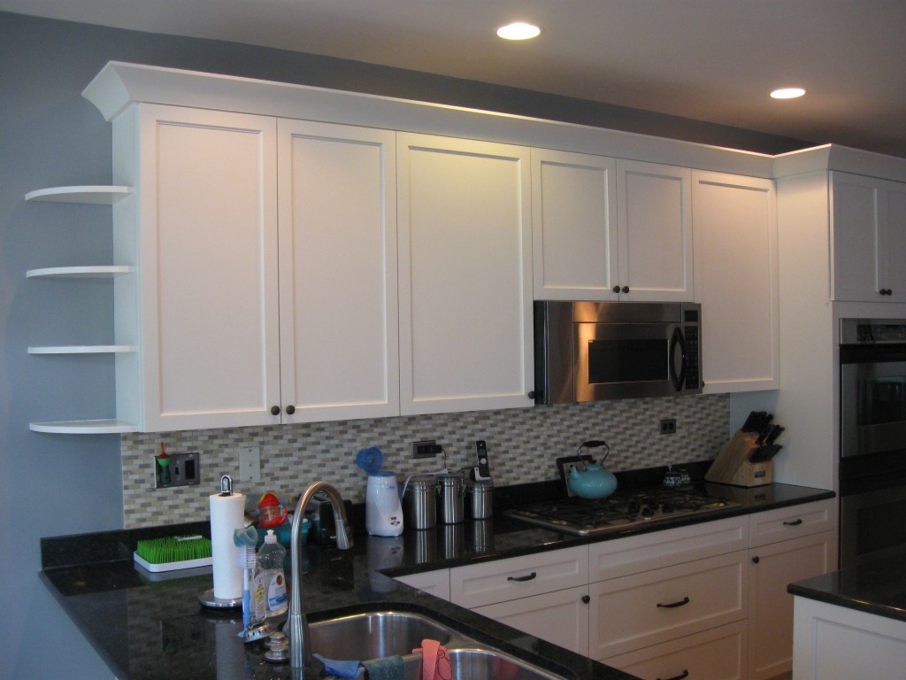 These cabinets in Glen Ellyn were refaced in maple with a linen white finish and no glaze. The inside edge of the doors has a subtle arch profile that is echoed in the crown molding.